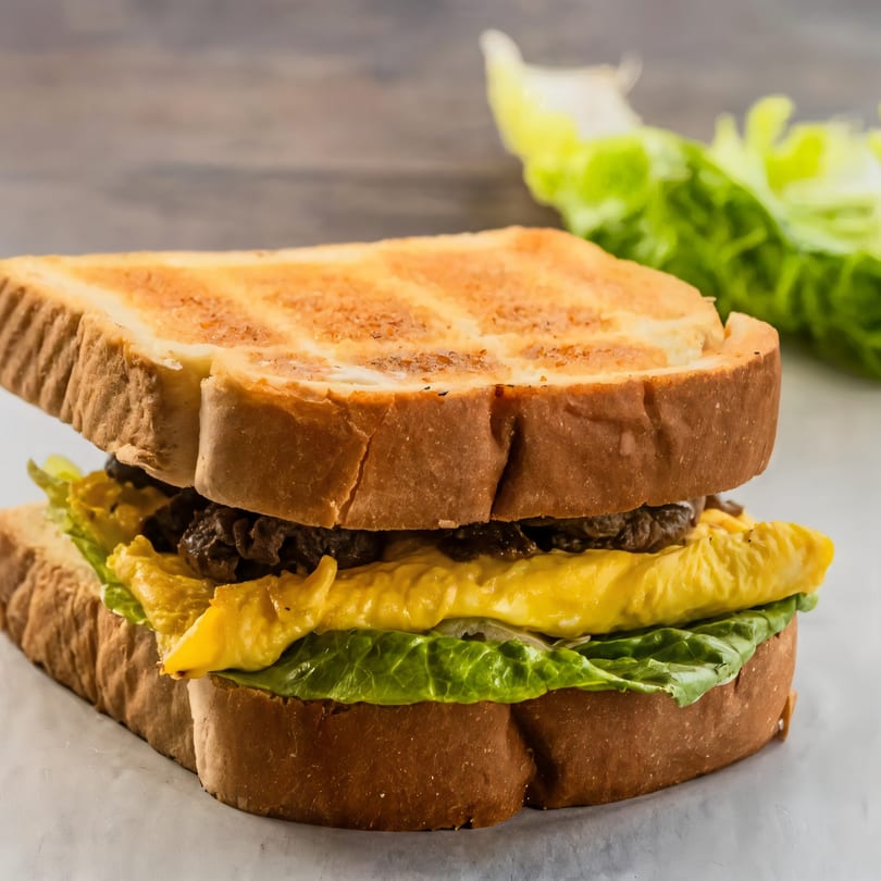 A Korean street toast sandwich with toasted bread, egg, bulgogi, and lettuce.